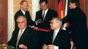1992. Německý kancléř Helmut Kohl (vlevo) a český premiér Václav Klaus podepisují deklaraci. V pozadí uprostřed stojí ministr zahraničí Německa Klaus Kinkel