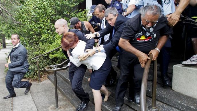 Julia Gillardová si s pomocí své ochranky razí cestu skrze dav protestujících Julia Gillardová si s pomocí své ochranky razí cestu skrze dav protestujících