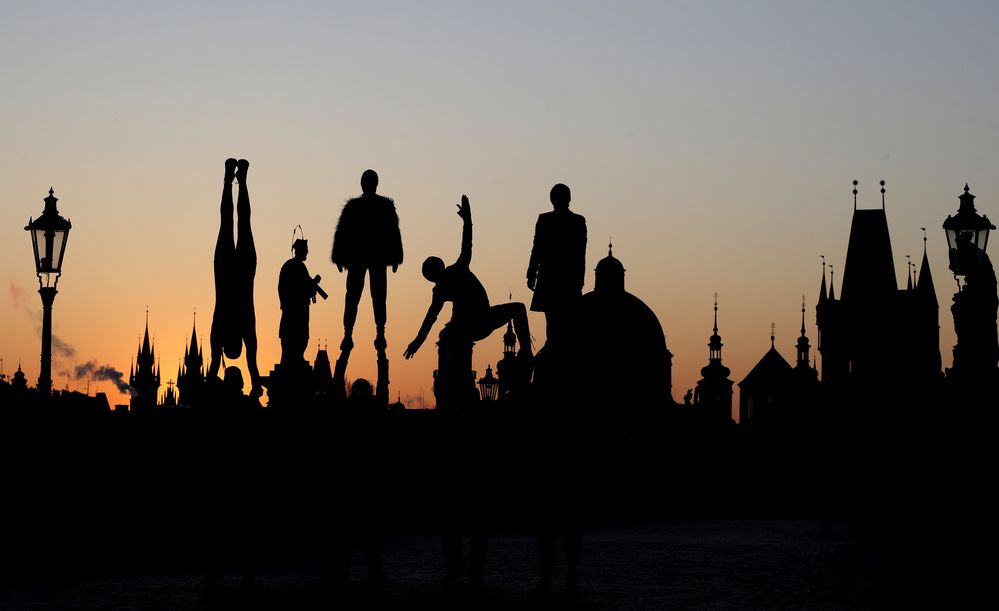 Duben 2020: Siluety umělců vystupujících při západu slunce na téměř prázdném Karlově mostě v Praze, Česká republika, čtvrtek 2. dubna 2020.