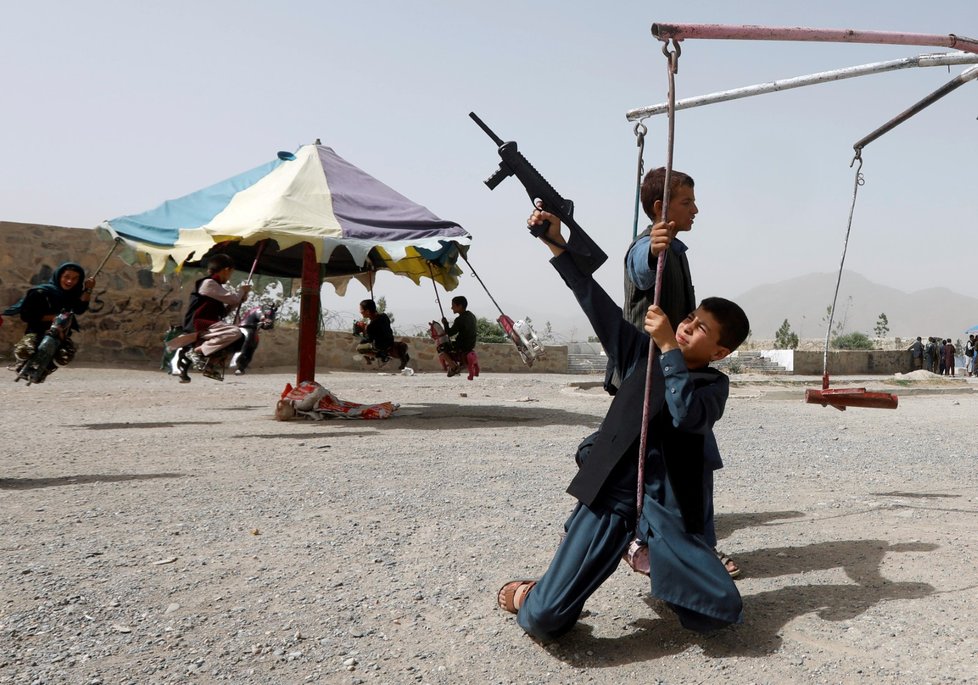Afghánský chlapec si hraje se samopalem.