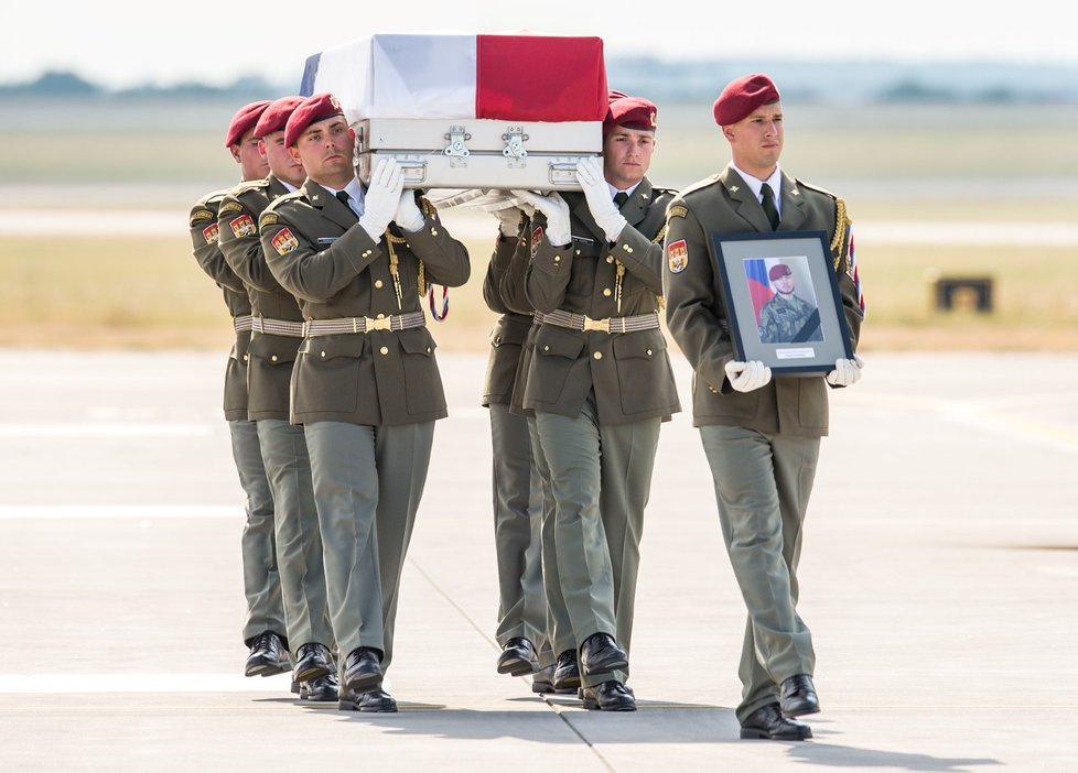 Rakve s ostatky těl vynesli vojáci postupně na letištní plochu. V čele šel voják nesoucí fotografii padlého.