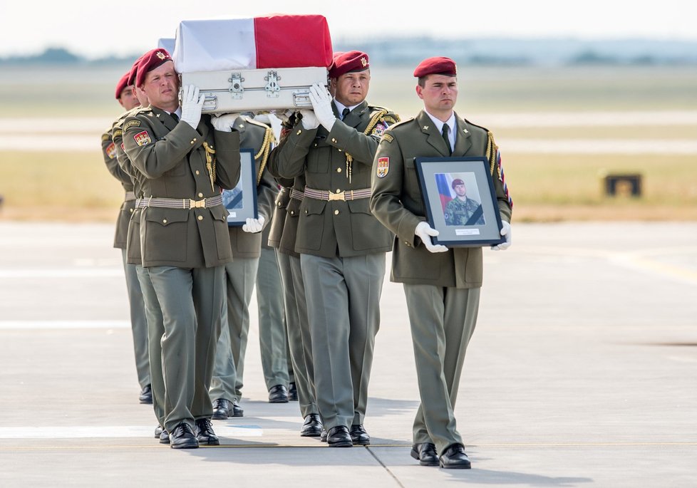 Rakve s ostatky těl vynesli vojáci postupně na letištní plochu. V čele šel voják nesoucí fotografii padlého.