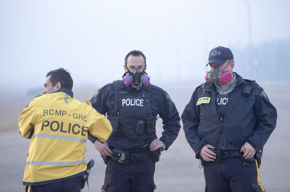Policisté se chrání před dýmem z požáru v kanadské provincii Alberta.