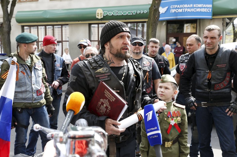 Alexandr „Chirurg“ Zaldostanov před tiskovou konferencí. Všimněte si malého chlapce ve vojenské kombinéze.