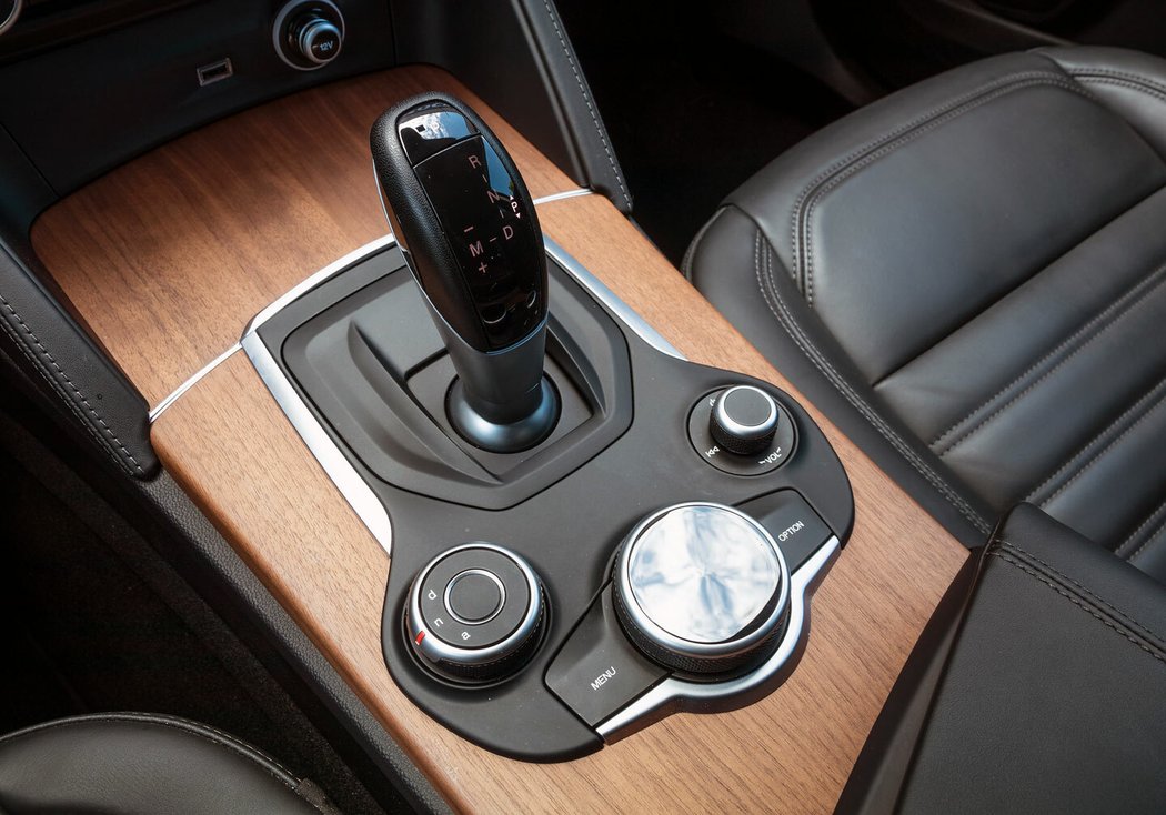 Výhradní volbou je automatická převodovka. Vedle ní volič jízdních režimů, níže ovladač audiosystému. Potěší též samostatné a dobře nahmatatelné ovládání hlasitosti po vzoru tehdejších vozů Audi.