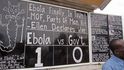 Alfred Sirleaf, který se věnuje komentování sociální situace v Libérii před ironickou tabulí hlásající, že ebola zatím vyhrává jedna-nula
