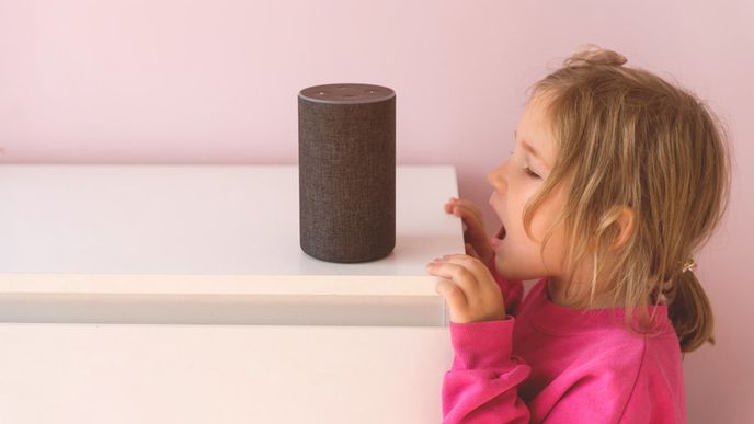Holčička prostřednictvím chytrého reproduktoru Amazonu Echo Dot komunikuje s virtuálním asistentem Alexa.