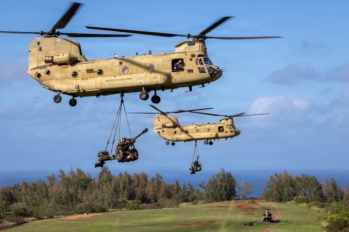 Dva vrtulníky CH-47 Chinook od 3. praporu 25. leteckého pluku, 25. bojové letecké brigády, přepravují v podvěsu houfnice M119 během vzdušně-výsadkových operací ve výcvikovém prostoru Kahuku na Havaji 14. listopadu 2025. Dva vrtulníky CH-47 Chinook od 3. praporu 25. leteckého pluku, 25. bojové letecké brigády, přepravují v podvěsu houfnice M119 během vzdušně-výsadkových operací ve výcvikovém prostoru Kahuku na Havaji 14. listopadu 2025.