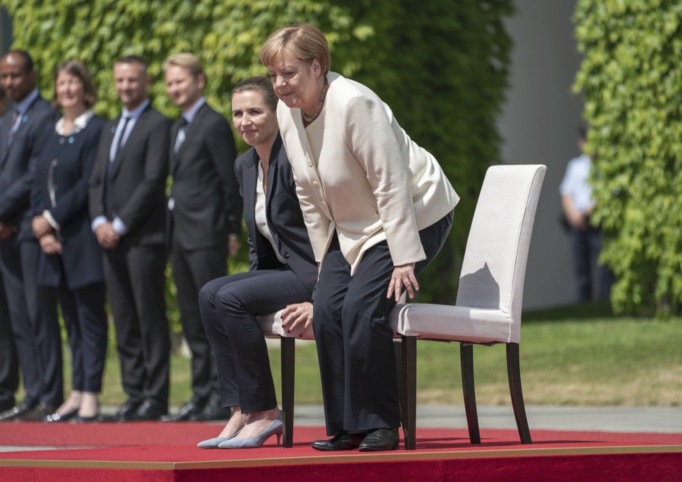 Německá kancléřka Angela Merkelová si den po třetím třesu na ceremonii s dánskou premiérkou Mette Frederiksenovou radši sedla (11. 7. 2019).