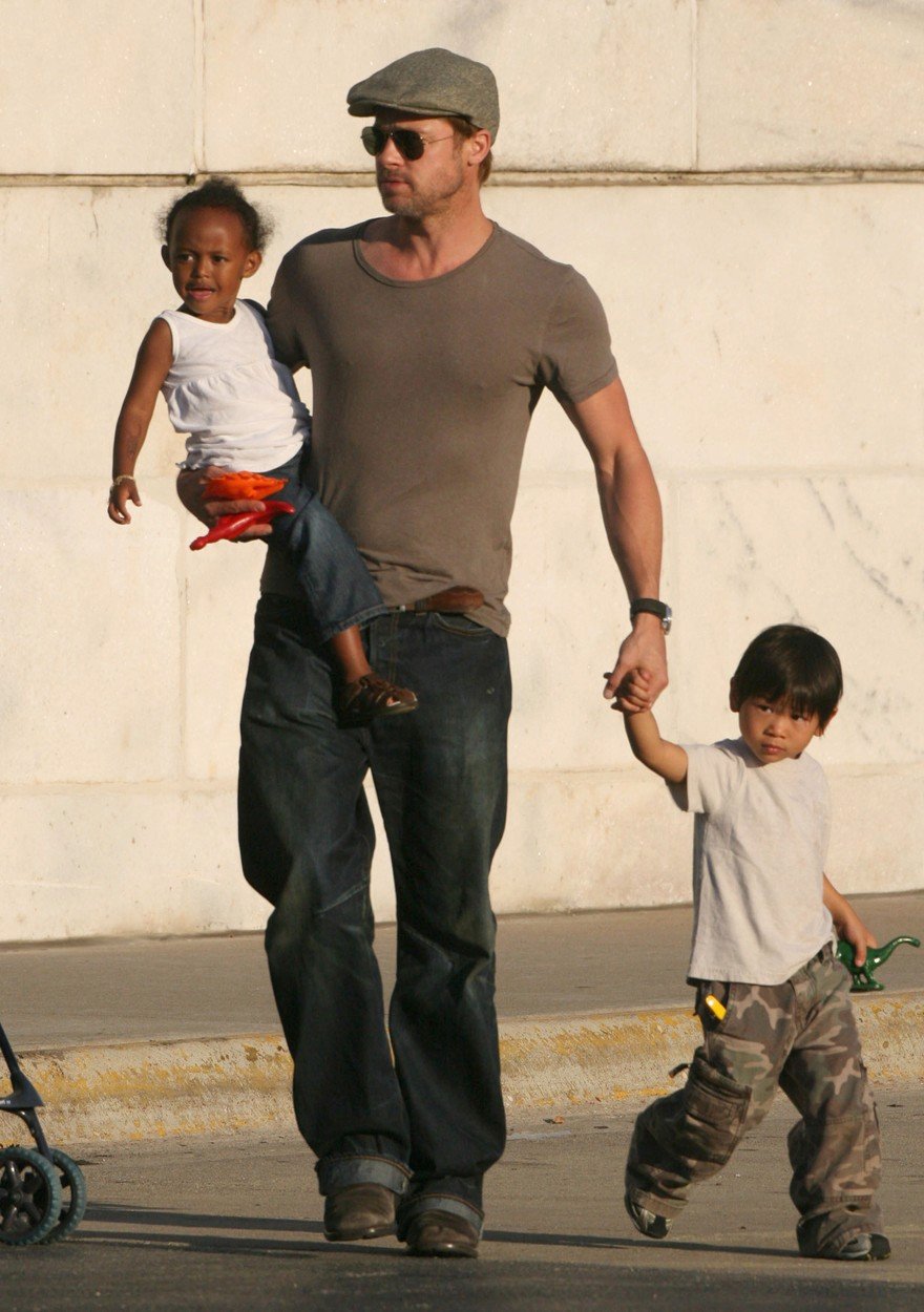 Brad Pitt drží za ruku syna Paxe Thiena a na ruce má Zaharu Marley (2007).