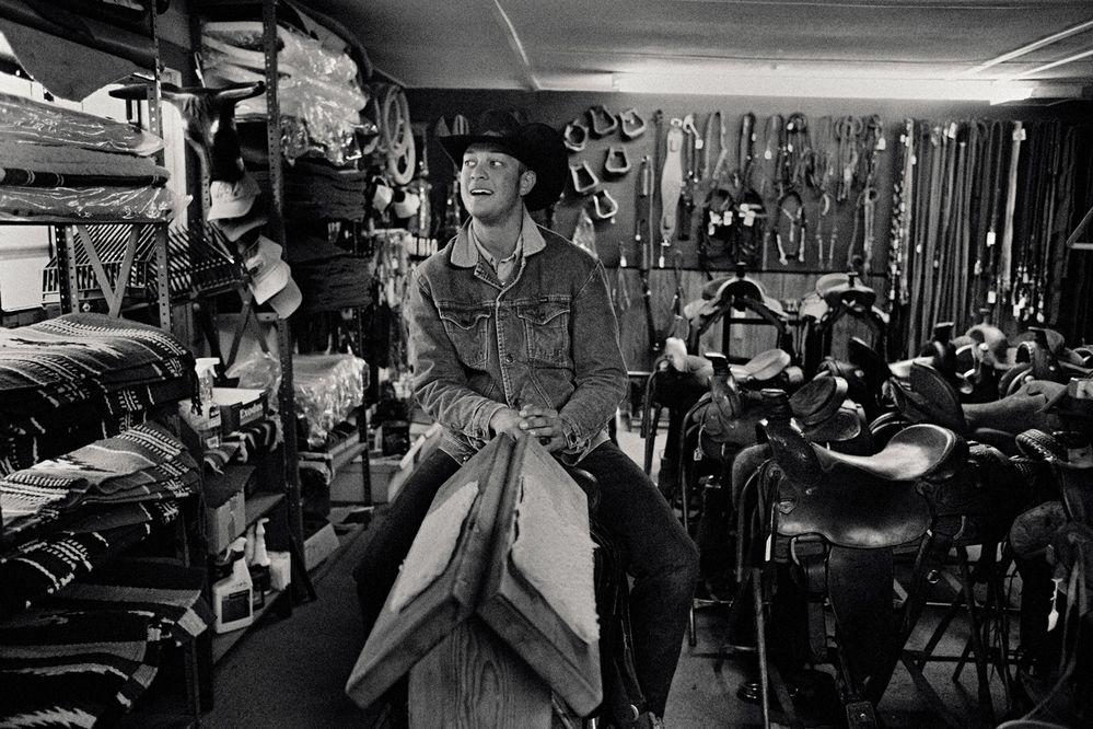 Pravý texaský kovboj zkouší sedlo v místním cowboy store (Texas)