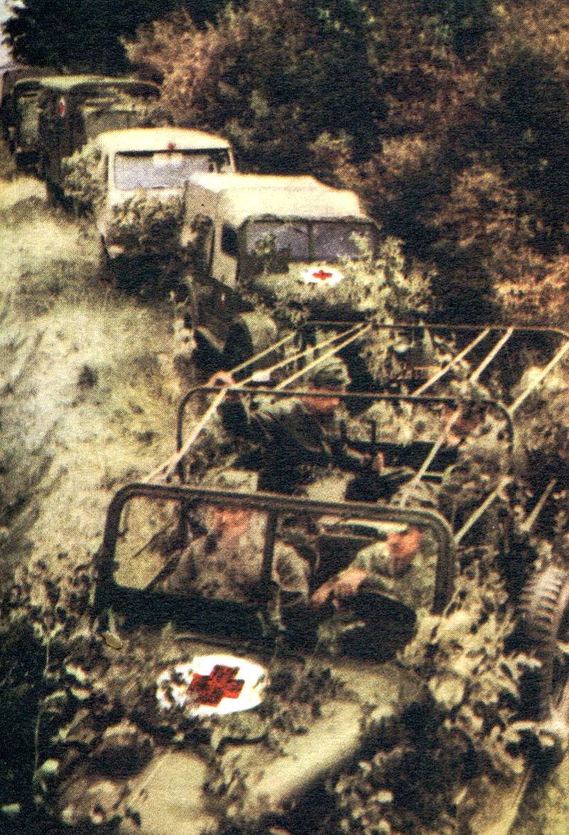 Celkem dobře zamaskovaná kolona zdravotnických vozů Československé lidové armády začátkem 60. let 20. století postupuje při jednom z mnoha vojenských cvičení. V konvoji se dají rozeznat vozidla GAZ-69, UAZ 450A, Praga V3S a Tatra 805.