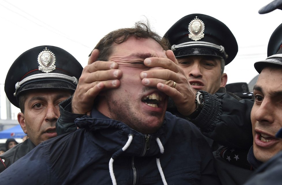 Arménský policista drží za tvář jednoho z demonstrantů, kteří v ulicích Jerevanu požadují odstoupení premiéra Serže Sargsjana (22.4.2018)