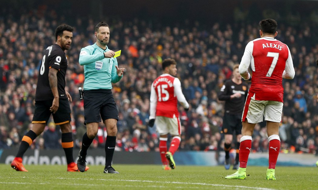 Sudí Mark Clattenburg ukazuje žlutou kartu Alexisovi z Arsenalu