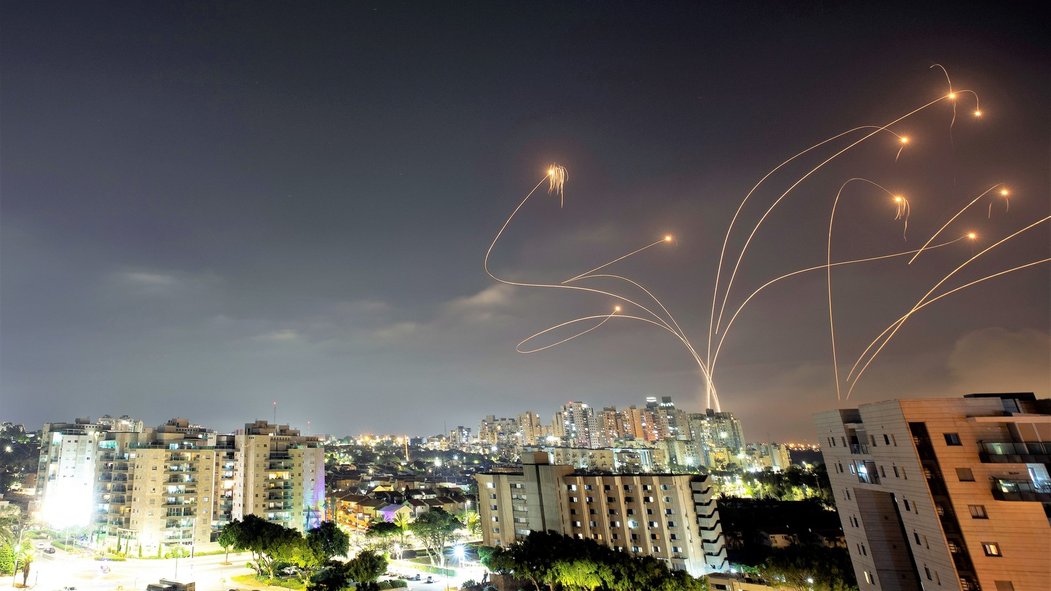 Noční nebe nad izraelským městem Aškelon ozařují střely systému Iron Dome ničící palestinské rakety.