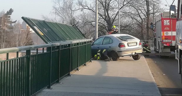 Auto viselo z mostu nad tratí ve výšce asi deset metrů.