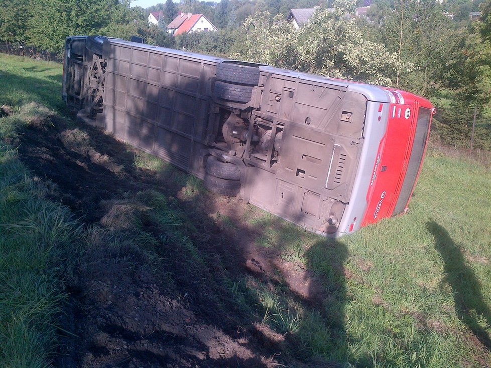 Převrácený autobus skončil mimo vozovku.