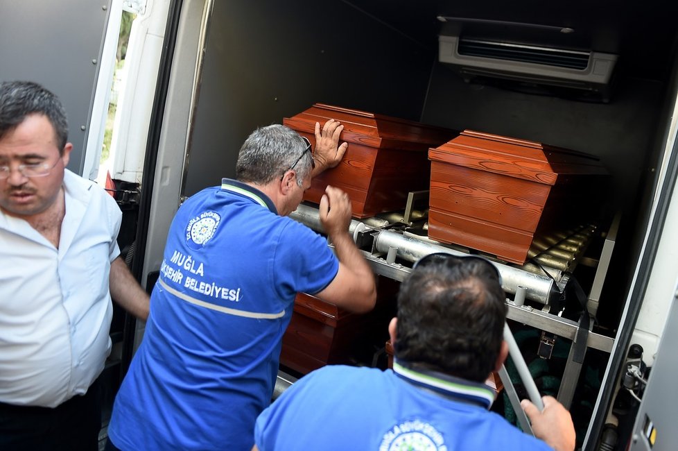 Pohřební služba nakládá rakve s ostatky tří členů zesnulé syrské rodiny.