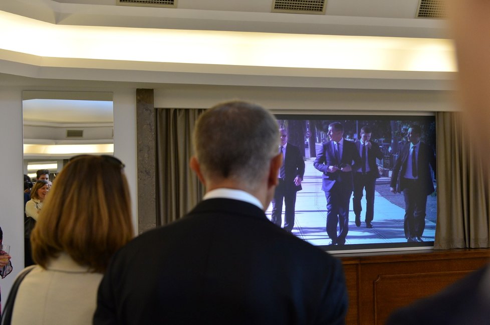 Součástí výstavy je také video z Babišových zahraničních cest. Premiér pozoruje v televizi sám sebe (8. 5. 2019)