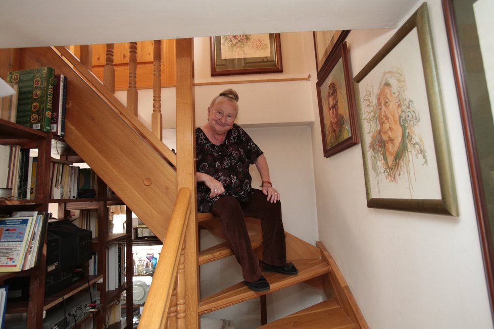 Dřevěné schodiště je lemováno Altmannovými obrazy.