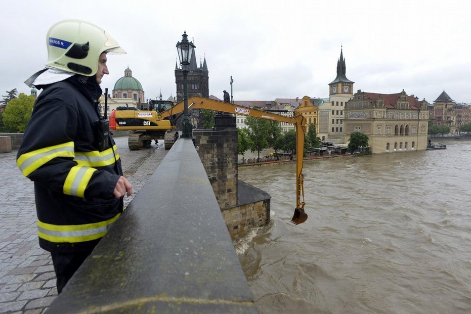 Bagr odklízí naplaveniny na uzavřeném Karlově mostě v Praze při povodni 3. června, kdy Vltava v místě kulminovala.