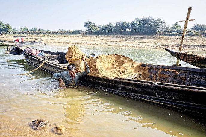 Přenášení říčního písku v proutěném koši z loďky do přistaveného náklaďáku na břeh Přenášení říčního písku v proutěném koši z loďky do přistaveného náklaďáku na břeh