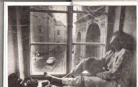 Jedinečná fotografie mladistvé Báry Basikové, jak z okna pokoje pozoruje historické centrum Prahy.
