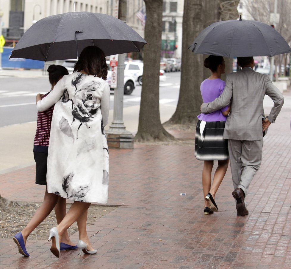 Prezident Obama kráčí pod deštníkem s dcerou Maliou, první dáma s dcerou Natashou.