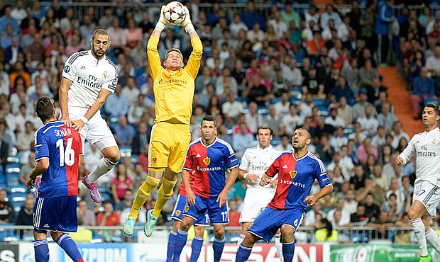 Brankář Basileje Tomáš Vaclík stahuje ze vzduchu centr před útočníkem Realu Madrid Karimem Benzemou.
