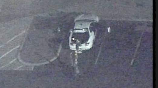 Policejní robot, který odhaluje výbušniny, prozkoumává opuštěné auto na parkovišti před kinem, kde došlo k masakru