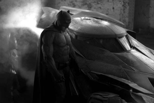 Ben Affleck jako Batman před svým Batmobilem.