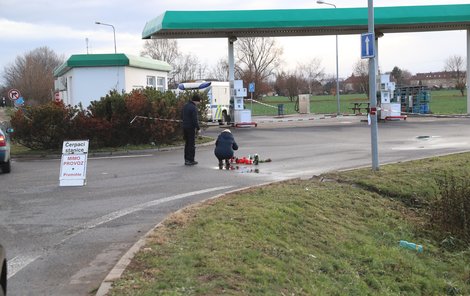 Na benzince, kde se vražda stala, lidé zapalují svíčky.