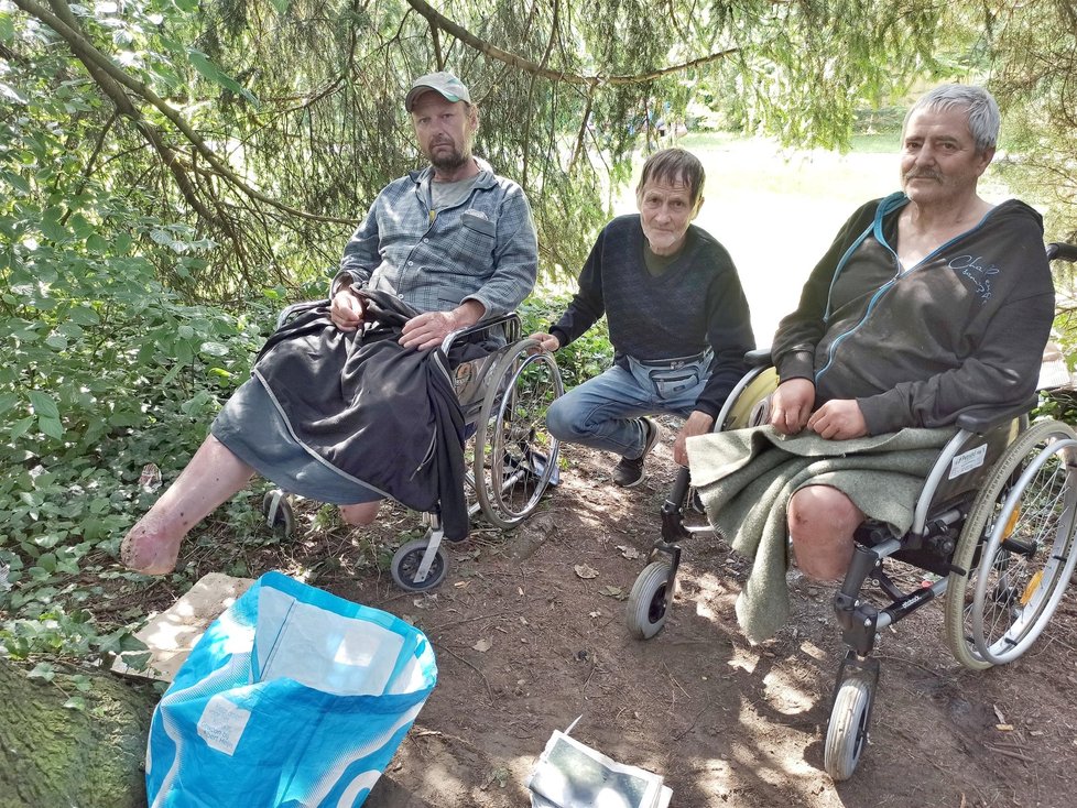 Bezdomovci s amputovanými nohami Petr a Libor (vpravo) táboří ve Frýdku-Místku pod košatým stromem. Jiří (uprostřed) jim občas pomáhá.