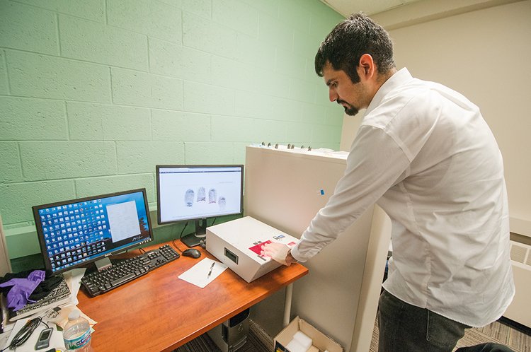 Vědec z Michiganské státní univerzity testuje ruku z 3D tiskárny na čtečce otisků prstů