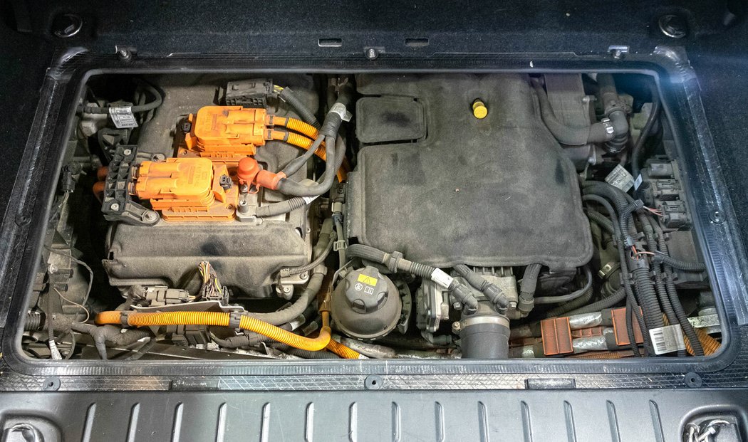 Po odšroubování podlahy zadního kufru lze získat přístup ke spalovacímu motoru (vpravo) i elektromotoru s výkonovou elektronikou (vlevo)
