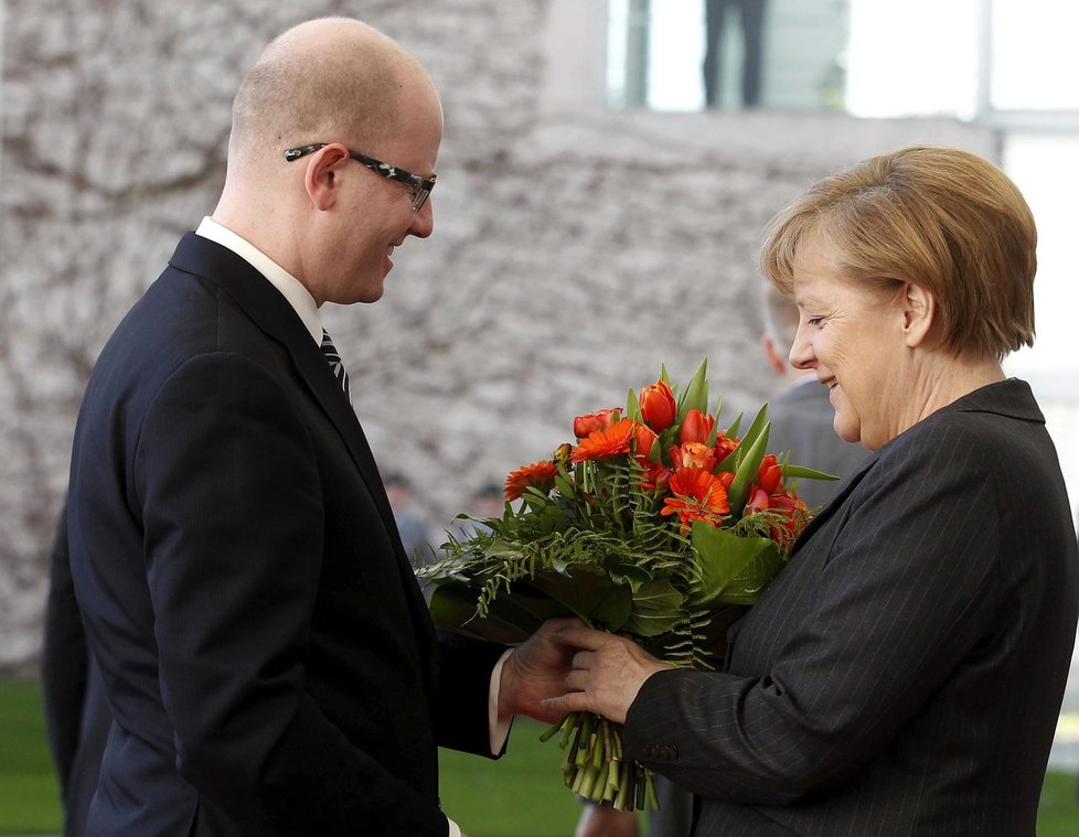 Premiér Bohuslav Sobotka předává květinu kancléřce Angele Merkelové.