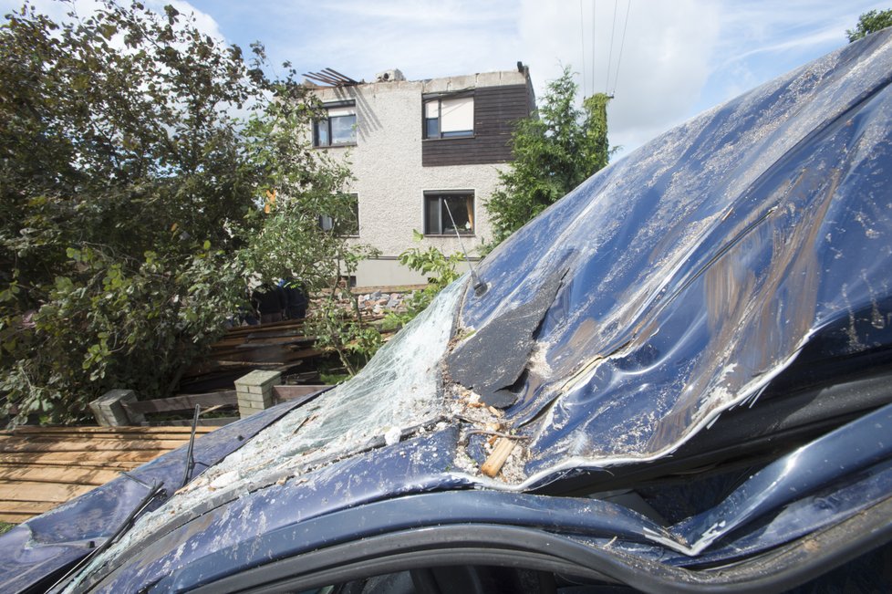 Zhruba osmdesát domů poškodila větrná smršť, která se v pátek 11. srpna kolem 17:30 prohnala Bohuslavicemi na Náchodsku. Nikdo nebyl zraněn, škody budou v milionech korun. Na snímku z 12. srpna vpředu je poškozené přední sklo vozidla, vzadu dům se zničenou střechou.