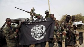 Nigerijští vojáci drží vlajku Boko Haram z jejich obsazeného stanoviště.