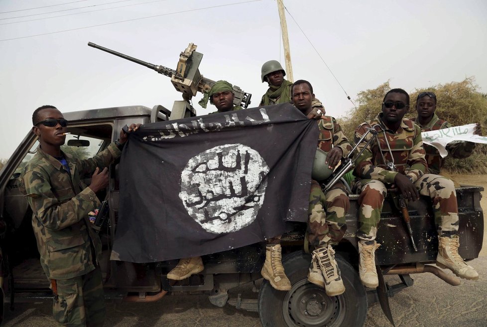 Nigerijští vojáci drží vlajku Boko Haram z jejich obsazeného stanoviště.