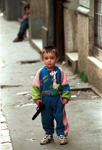 Bosenský chlapec si hraje s otcovou pistolí. Sarajevo, duben 1994.