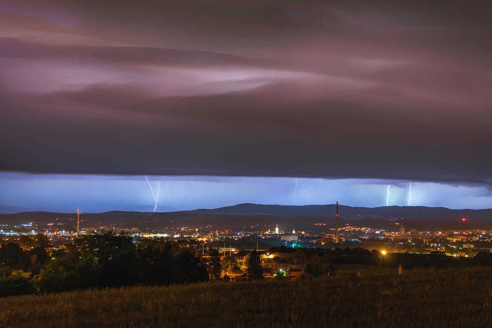 Na jihočeskou a jihočeskou metropoli se valí bouřkový mrak. Horizont ozařují blesky.