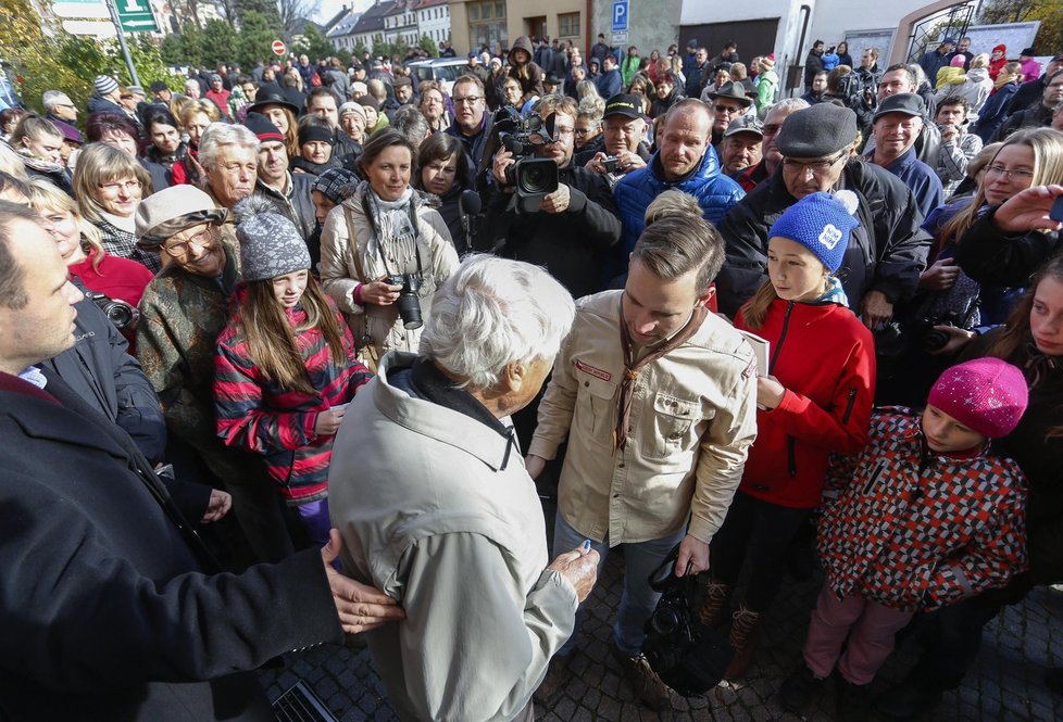 Pamětníka holokaustu Jiřího Bradyho (vpředu uprostřed zády) uvítalo 30. záři na náměstí před radnicí v jeho rodném Novém Městě na Moravě kolem 400 lidí.