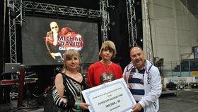 Michal David předává v Břeclavi šek na 100 tisíc korun napadenému Petrovi (15) a jeho mamince Oksaně. Peníze rodina vloží do nadačního fondu.