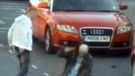 Muži bijí do mladého muže a auta kolem projíždějí, jako by se nic nedělo