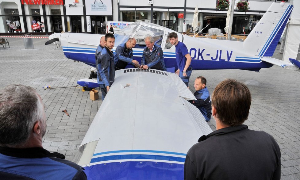 Mechanici kompletují sportovní letoun Zlín Z-42M na vernisáži letadel a &#34;kosmického stanu&#34; na brněnském náměstí Svobody.
