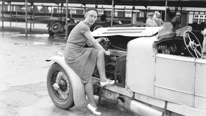 Kitty Brunell pracuje na motoru svého AC Ace Sports. Kitty je historicky jedinou ženou, která kdy vyhrála British RAC Rally. Stalo se tak v roce 1933, tedy rok poté, co byla na okruhu Brooklands pořízena tato fotografie.