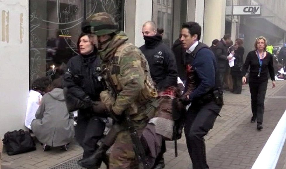 Policisté a voják odnášejí raněného z bruselského metra.
