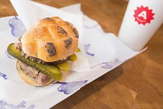 Česká verze burgeru z Naše maso v makové housce, s okurkou, cibulí a hovězím masem
