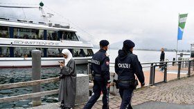Policisté míjí ženu v hidžábu.