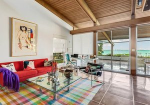 Jedné polovině obývacího pokoje dominuje červená pohovka obklopená moderním uměním.